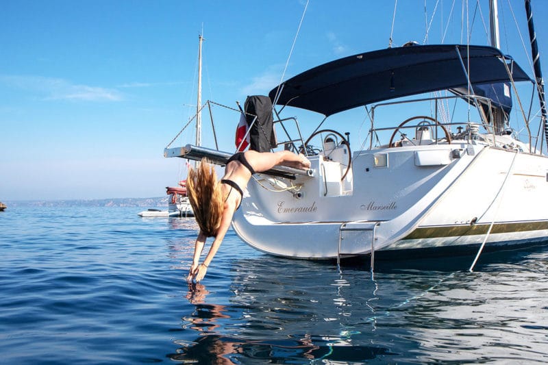 Jeune femme qui plonge dans la Méditerranée depuis un voilier Oceanis 473
