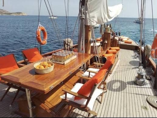 Grande table en bois verni sur le pont du voilier Hygie